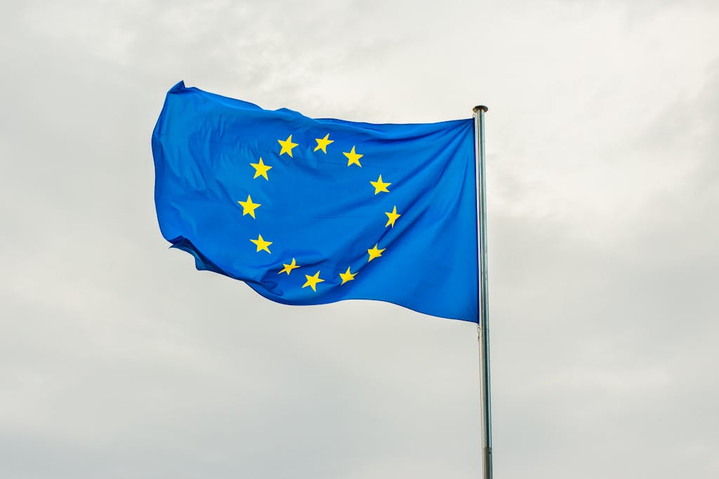 The European Union flag gracefully waving on a flagpole against a cloudy sky in Strasbourg, France.