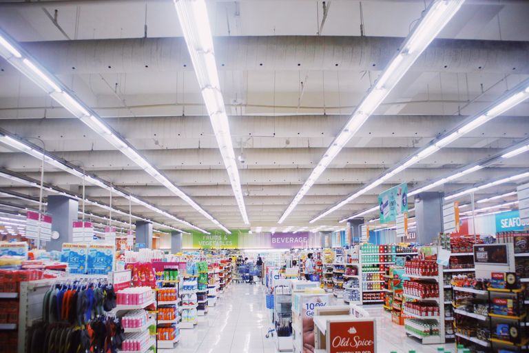 Interior of modern supermarket with various shelves with assorted colorful products under bright lamps